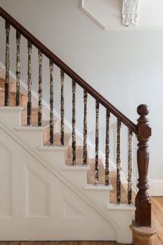 a stair case next to a wooden banister in a house with white walls and wood floors