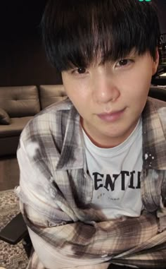 a young man sitting on top of a couch in front of a table with a cell phone