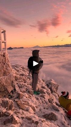 a man standing on top of a snow covered mountain next to a lifeguard chair