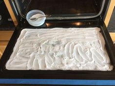 a pan filled with white frosting next to an oven