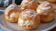 several pastries on a plate with powdered sugar and cream in the middle, sitting on a table