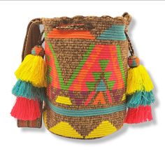 Magestic large traditional Wayuu backpack, beige background color, ethnic design in vibrant tropical colors, sash-type woven handle in the same hue as the backpack, decorated with braided cord with bell-ringers in the same color as the handle. Woven 100% by hand by our indigenous artisans from the Wayuu community of the Colombian Alta Guajira. -Material: Industrial wool -Height: 11.5" -Width: 12in -Length: 8in -Handle: 41 in long x 2.5in wide *The measurements of this product may vary slightly, Traditional Multicolor Backpack For Travel, Traditional Straw Bag With Adjustable Strap For Travel, Bohemian Multicolor Bucket Bag For Travel, Bohemian Beige Backpack, Bohemian Multicolor Bucket Bag With Adjustable Strap, Multicolor Woven Crochet Bag For Festival, Festival Multicolor Crochet Woven Bag, Multicolor Backpack With Adjustable Strap For Festivals, Bohemian Natural Color Backpack