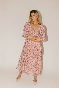 whether you’re searching for the perfect wedding guest dress, or for an excuse to feel like a princess, this puff sleeve midi dress does not disappoint. it features a stunning pink vintage floral pattern, dramatic puff sleeves, + a flirty corset-inspired bodice. the perfect long formal dress for garden parties, fancy dinners, + anytime you feel like frolicking. pink + purple floral // midi length, scoop neckline, dramatic puff sleeves, back zipper closure, smocked bodice, fully lined model is 5' Modest Floral Print Dress With Puff Sleeves, Pink Floral Print Maxi Dress With Puff Sleeves, Feminine Midi-length Floral Dress With Rose Print, Feminine Floral Print Midi Dress, Feminine Midi Dress With Floral Print, Flowy Floral Print Maxi Dress With Puff Sleeves, Pink Floral Print Maxi Dress With Square Neck, Flowy Puff Sleeve Dress With Floral Print For Brunch, Pink Midi Dress With Smocked Bodice