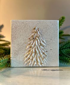 a christmas tree made out of sand sitting on top of a table next to evergreen branches