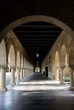 an empty walkway with arches and lamps hanging from the ceiling