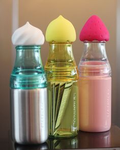 three different colored bottles sitting on top of a table next to each other, one with an egg in it