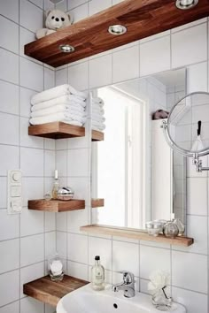 a bathroom with white tile and wooden shelves on the wall, along with a sink