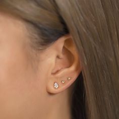 a close up of a woman's ear with three small diamond studs on it