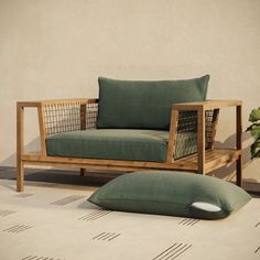 a couch and chair with pillows on the floor next to a potted plant in front of a wall