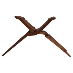 a wooden table with two crossed legs on the top and one leg raised up to the ground