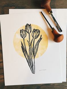 some flowers are sitting on top of a piece of paper next to a pair of paintbrushes