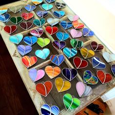 a wooden table topped with lots of stained glass hearts