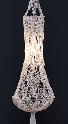 a white light hanging from the side of a lamp with tassels on it