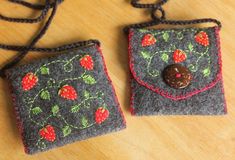 two small purses with buttons on them sitting on a wooden table next to each other