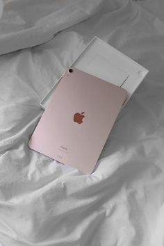 an apple ipad is laying on a bed with white sheets and sheet covering it's surface