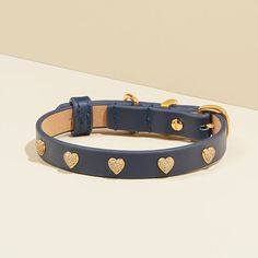 a blue leather dog collar with gold hearts on the front and back, sitting on a white surface