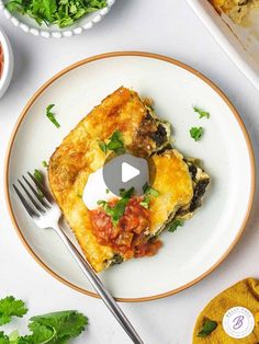 a white plate topped with an omelet covered in cheese and sauce next to other dishes