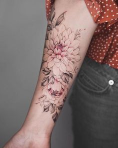 a woman's arm with a flower tattoo on the left side of her arm