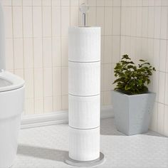 a white toilet sitting in a bathroom next to a plant on top of a pedestal