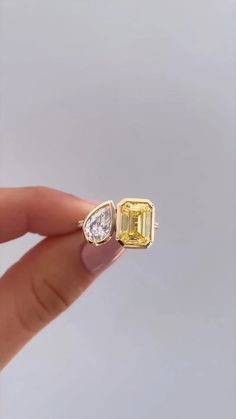 a person holding an engagement ring with a yellow and white diamond in it's middle