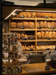 a bakery filled with lots of breads and pastries on shelves next to each other