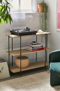 a record player is on top of a shelf next to a chair and potted plant