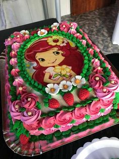 there is a cake decorated with flowers and a little mermaid on it's side