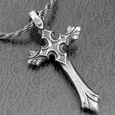 a silver cross is shown on a gray surface with an intricate pattern in the background