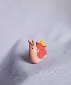 a snail figurine sitting on top of a white sheet with a yellow hat