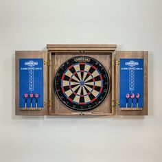 a dart board mounted to the side of a wall with darts on it and two plaques