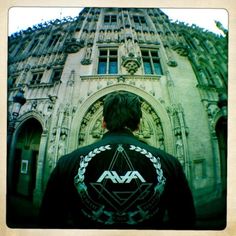 a man standing in front of an old building wearing a jacket with the letters aa on it