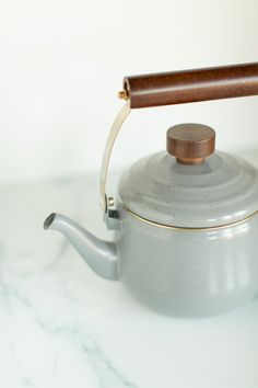 a tea kettle with a wooden handle on a marble table