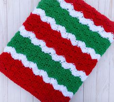 a red, white and green crocheted dishcloth sitting on top of a wooden table