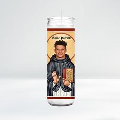 a candle with an image of a saint patrick holding a book in his right hand