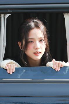 a young woman looking out the window of a car with her hands on the windowsill