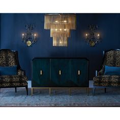 two chairs and a cabinet in front of a blue wall with gold chandeliers