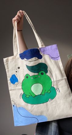 An Acrylic painted cartoon frog original design. On a tote bag with the shoulder strap with a matching burlap pouch sole separately. Takes 1 - 2 weeks before out for shipping with An Post. If washing hand wash in lukewarm water. Toat Bags Painted, Painting On Bags Ideas, Design Totebag, Casual Everyday Hand Painted Bag, Casual Hand Painted Bags For Gift, Tote Bag Drawing, Casual Hand Painted Canvas Bag For Everyday Use, Casual Hand Painted Bags For Everyday, Everyday Use Hand Painted Green Bags