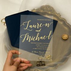 a person holding up a blue and gold wedding card