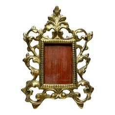 an ornate gold frame with a red wooden plaque in the center on a white background