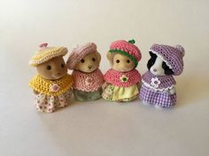 three small teddy bears are standing next to each other in crocheted dresses and hats