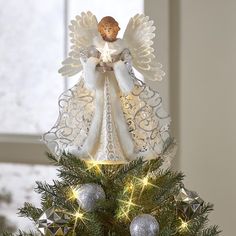 an angel figurine sitting on top of a christmas tree