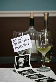 two wine glasses sitting on top of a table next to bottles and papers with signs