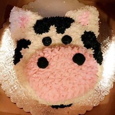 a cake that looks like a cow with pink and black frosting on it's face