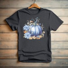 Welcome the beauty of fall with our stunning Blue Watercolor Pumpkin and Fall Flowers Unisex T-shirt! This cozy and stylish tee is a must-have addition to your autumn wardrobe. Key Features: Design: Our unique t-shirt showcases a hand-painted blue watercolor-style pumpkin surrounded by vibrant fall flowers, capturing the essence of the season. Comfort: Made from premium, soft material, this unisex tee offers exceptional comfort and durability, perfect for everyday wear. Versatile: Designed for b Blue Pre-shrunk T-shirt For Fall, Blue Crew Neck T-shirt For Fall, School Spirit Wear, Blue Pumpkin, Watercolor Pumpkin, Blue Pumpkins, Autumn Wardrobe, Watercolor Pumpkins, Unique T Shirt