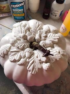 a white pumpkin sitting on top of a table next to other bottles and glues