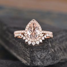 an engagement ring with a pear shaped morganite surrounded by small diamonds on top of a rock