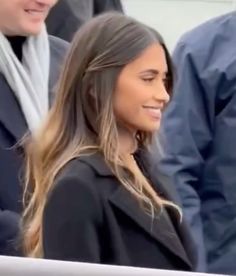 a woman with long hair standing next to other people