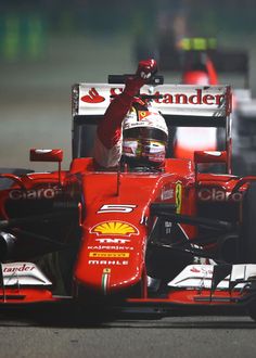 a man driving a red race car on top of a track