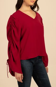 Oversized sleeves boasting a cinched design frame this V-neck top that's sure to make a statement. V-neck Long sleeves with adjustable tie cuffs 67% recycled polyester, 33% polyester Machine wash, dry flat Made in the USA of imported fabric Fall V-neck Top With Elastic Sleeves, Fall V-neck Puff Sleeve Top With Blouson Sleeves, V-neck Ruched Blouse For Brunch, Fall V-neck Top With Gathered Sleeves, Casual V-neck Top With Elastic Sleeves, Billowy V-neck Tops For Fall, Billowy Gathered Sleeves Tops For Fall, Fall Puff Sleeve V-neck Top With Blouson Sleeves, V-neck Tops With Gathered Sleeves For Brunch