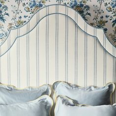 a white headboard with blue and yellow flowers on the wall next to two pillows